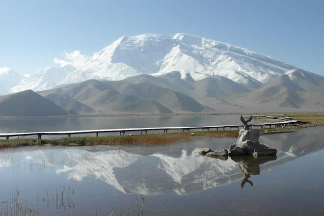 Akklimatisations-Trekking am Fuße des Eisriesen Muztagh Ata, 7.546 Meter hoch, der sich hier schön im Kara Kul See spiegelt. Foto: djd/DAKS - die Welt der Berge